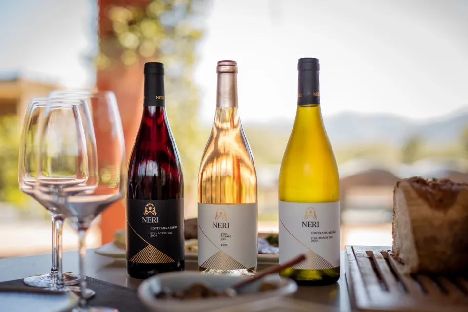 Tre bottiglie Neri, rosso, rosato e bianco, accanto a calici da degustazione